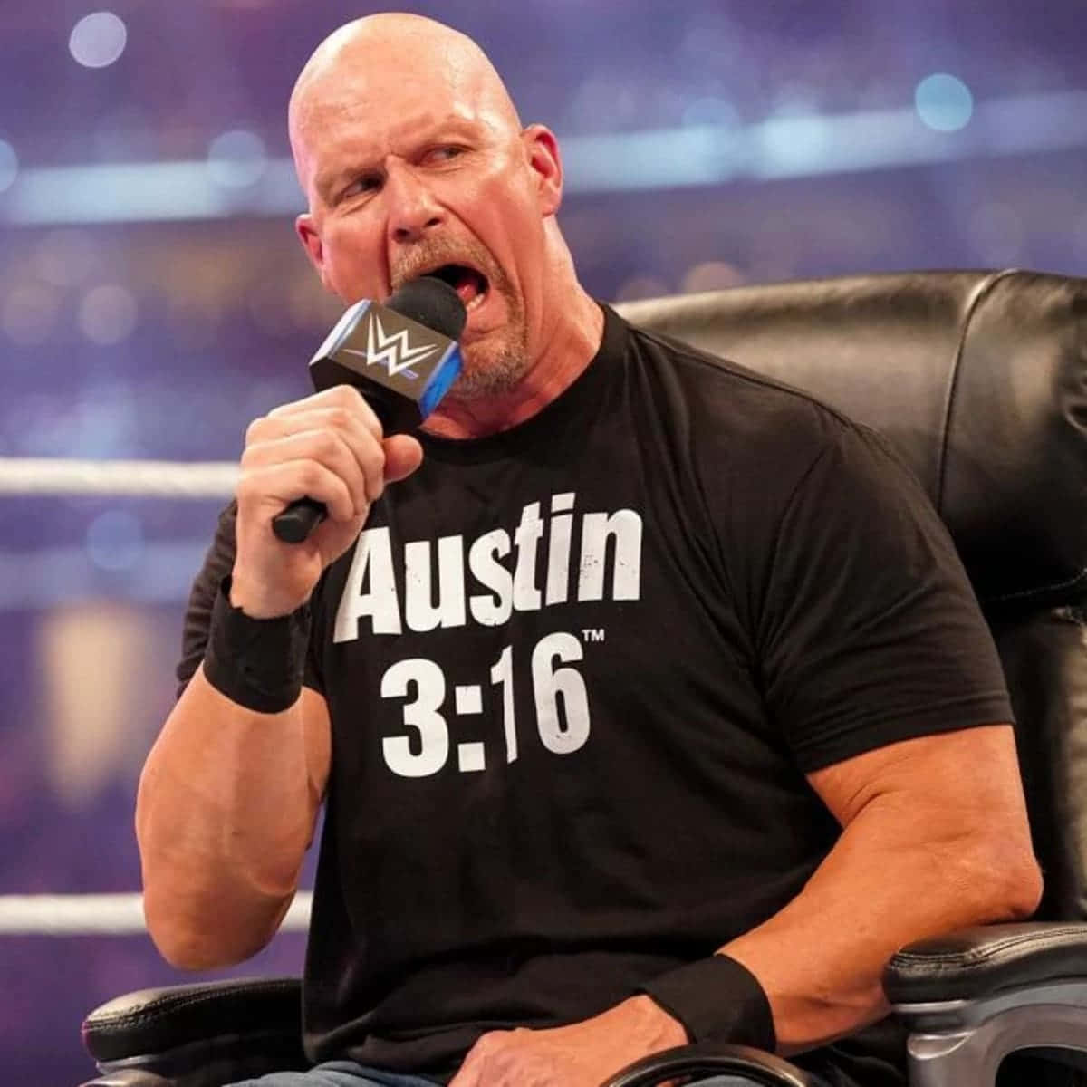 WWE 桌布 壁紙 — 光頭摔角手 Austin 3:16 坐在擂台內的黑色椅子上，對著 WWE 麥克風大喊。