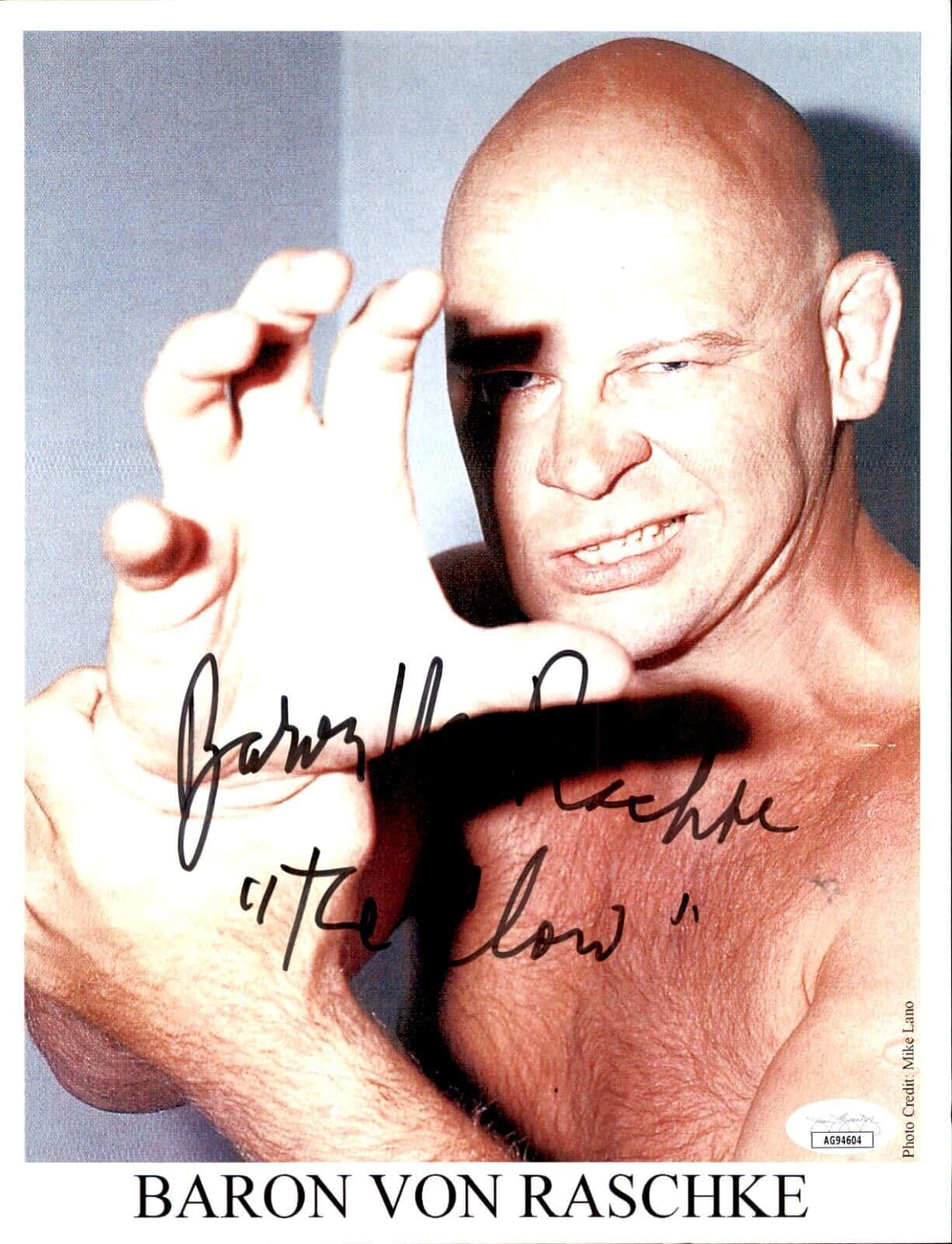 光頭摔角手 Baron von Raschke 微笑並舉起雙手，他的簽名清晰可見。 — King Von 壁紙