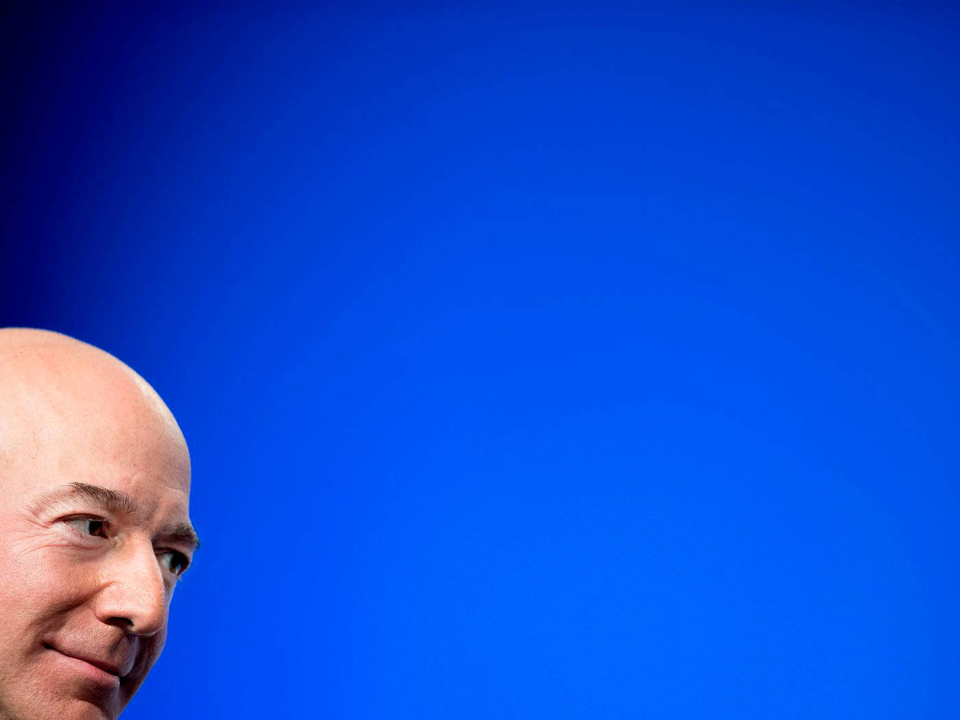 Bezos 桌布 壁紙 — 光頭男子微笑的特寫，背景為純藍色。