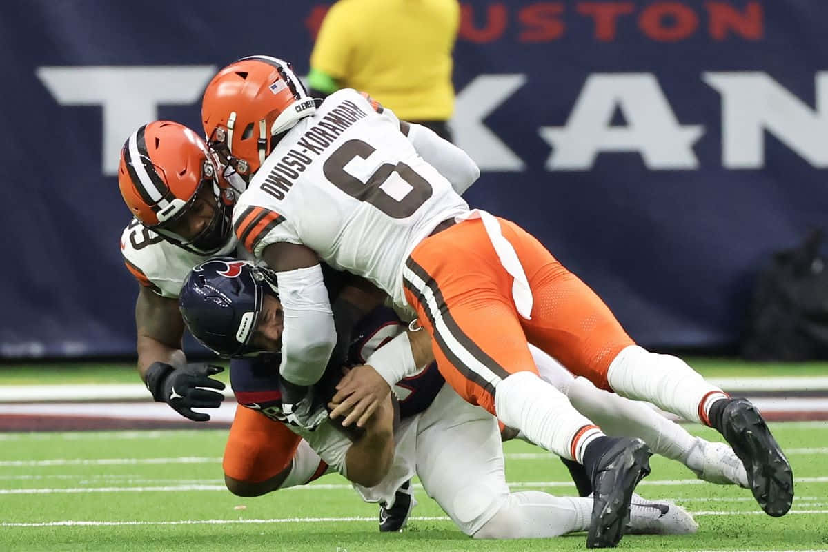  壁紙 — 克里夫蘭布朗隊60號球員在激烈的NFL比賽中擒抱休士頓德州人隊四分衛。