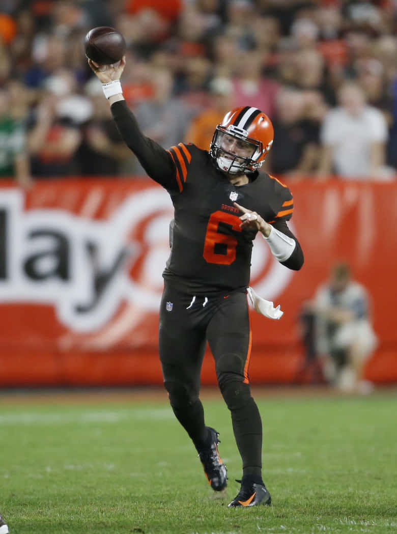 Baker Mayfield 桌布 壁紙 — 克里夫蘭布朗隊的四分衛身穿黑色和橙色球衣，在體育場燈光下的夜間比賽中投擲橄欖球。