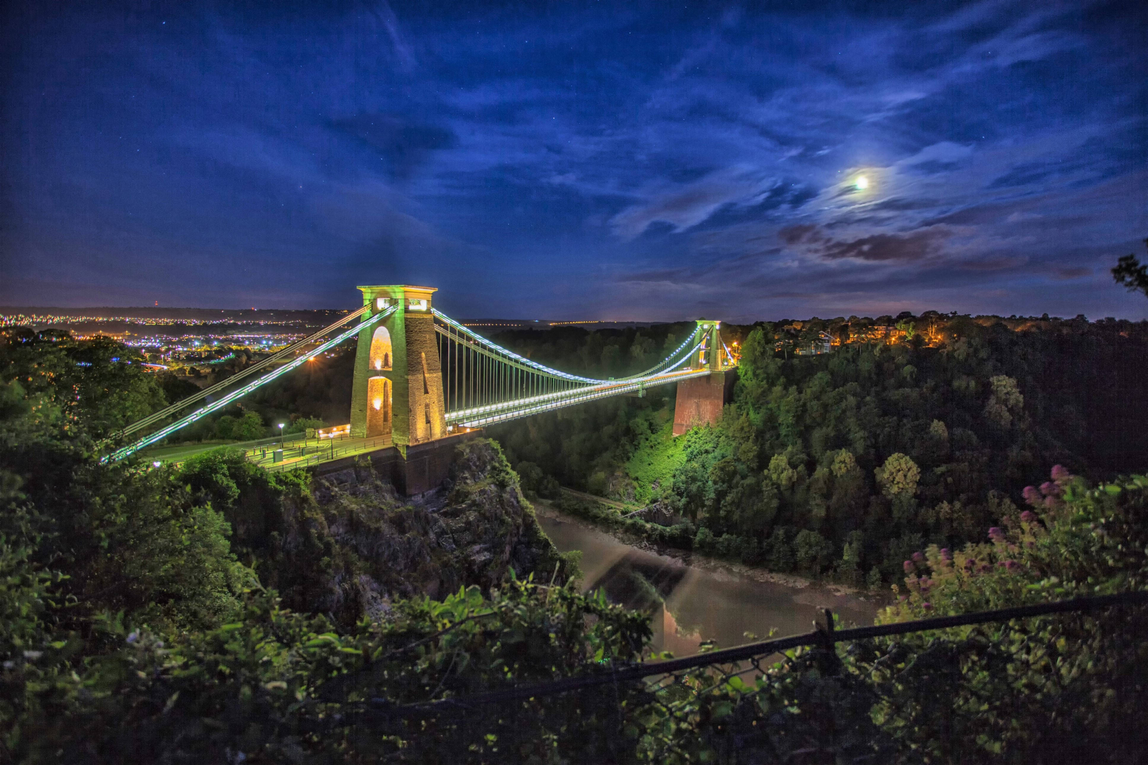 England 桌布 壁紙 — 克里夫頓吊橋在月光下閃耀，襯托著繁星點點的夜空，下方城市燈光閃爍。