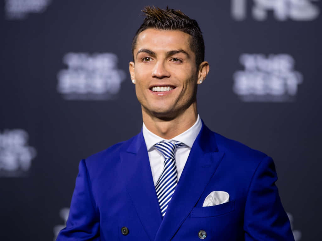 Ronaldo 桌布 壁紙 — 克里斯蒂亞諾·羅納度在深色品牌背景前，穿著一套俐落的藍色西裝自信微笑。