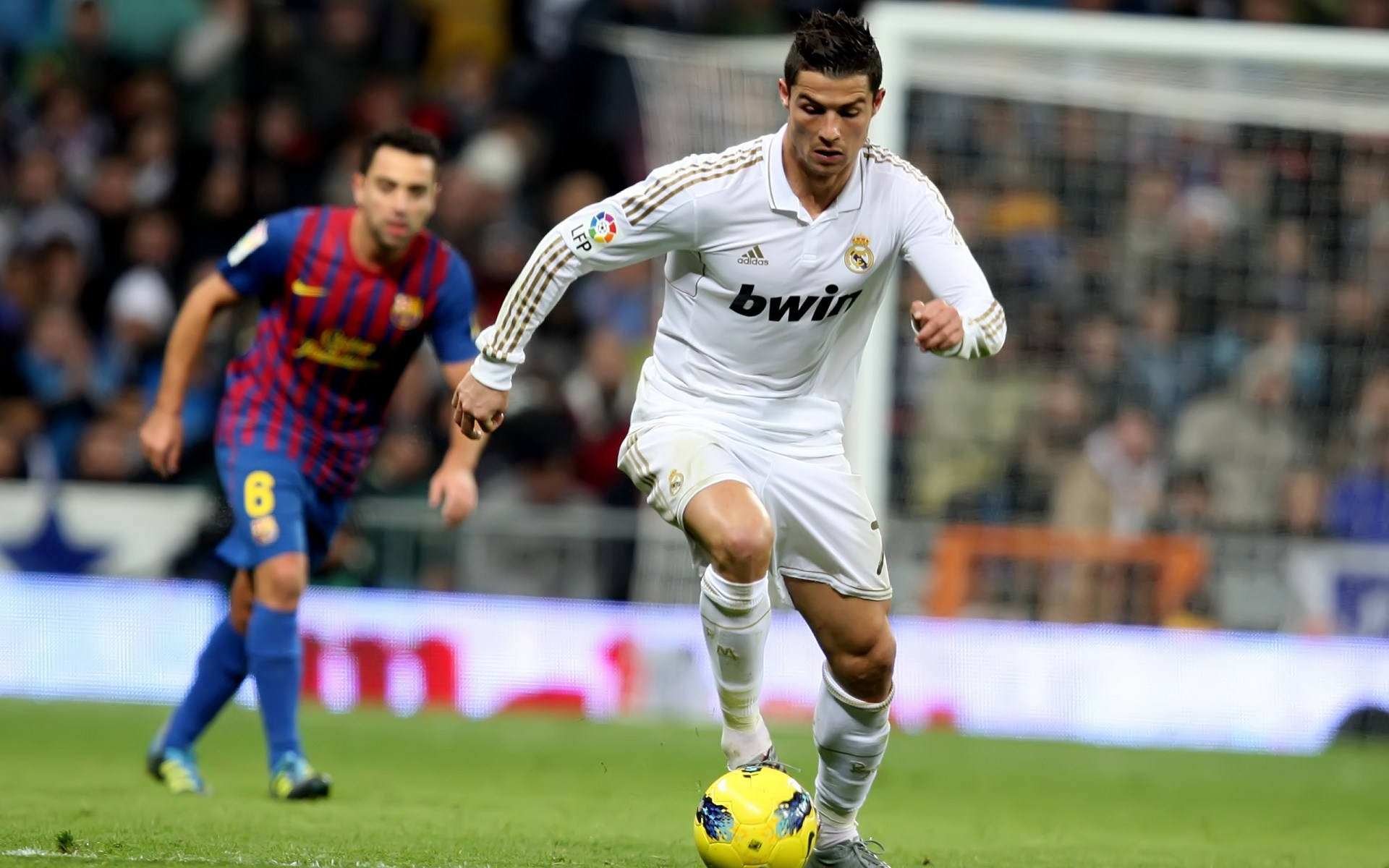 Cr7 桌布 壁紙 — 克里斯蒂亞諾·羅納度在綠色球場上盤帶一個黃色足球，一名身穿藍紅色的巴塞隆納球員正在追趕他。