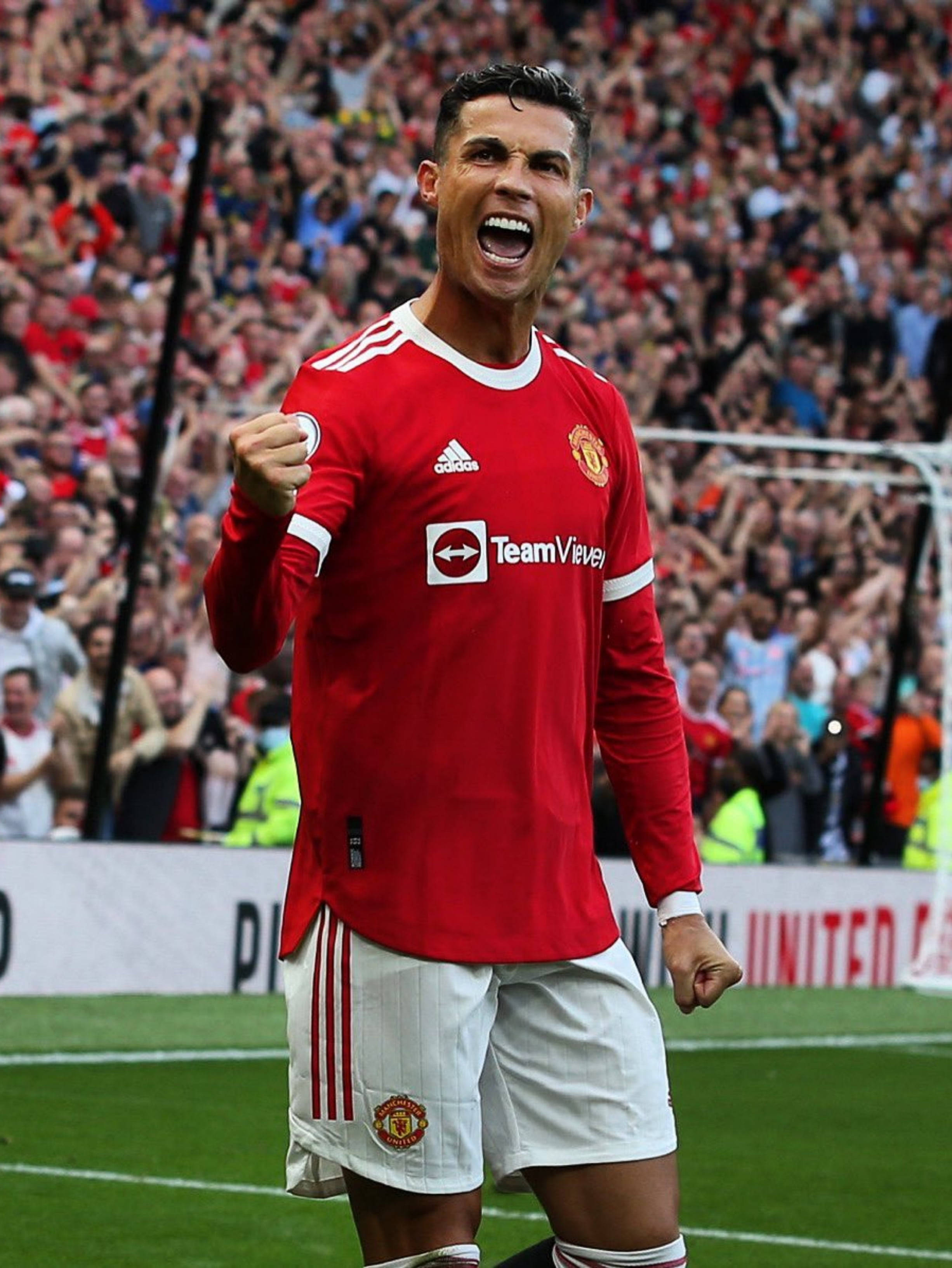 Ronaldo 桌布 壁紙 — 克里斯蒂亞諾·羅納度在陽光明媚的足球場上，穿著紅色曼聯球衣，背後有震耳欲聾的人群，熱情慶祝。