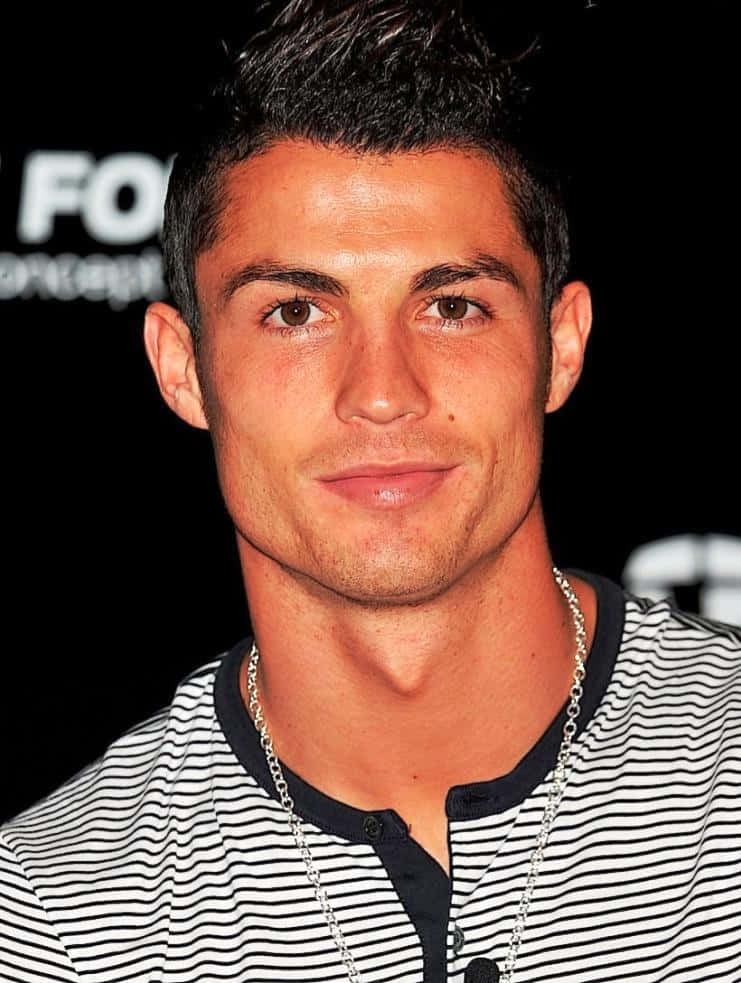Ronaldo 桌布 壁紙 — 克里斯蒂亞諾·羅納度的特寫肖像，他穿著黑白條紋襯衫，在深色背景前自信地微笑。