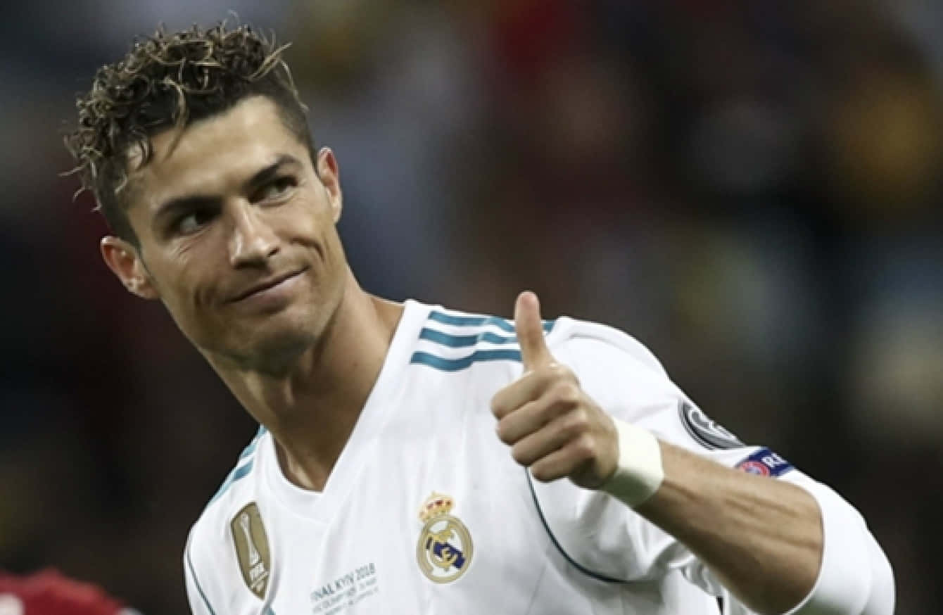 Ronaldo 桌布 壁紙 — 克里斯蒂亞諾·羅納度身穿白色皇家馬德里球衣，在比賽中自信地豎起大拇指，面帶微妙笑容。