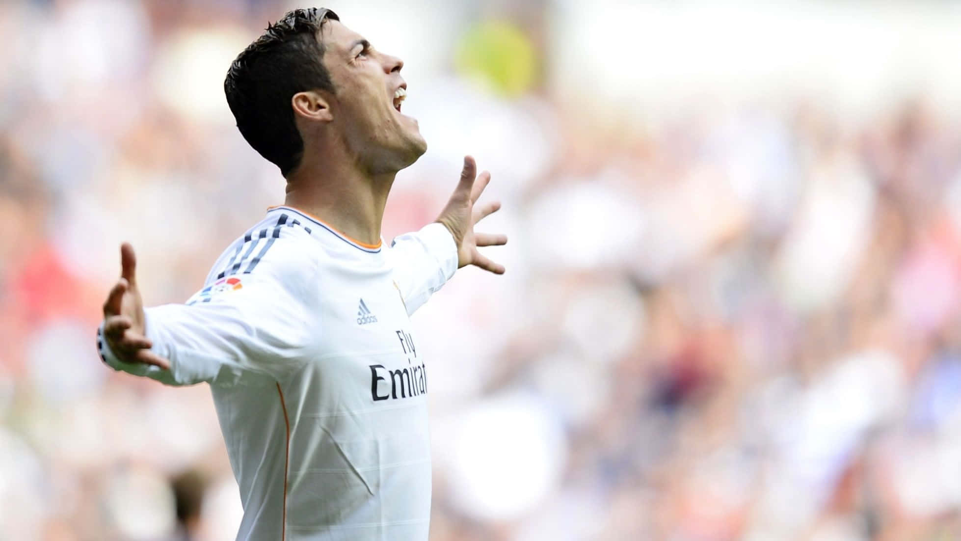 Ronaldo 桌布 壁紙 — 克里斯蒂亞諾·羅納度身穿白色皇家馬德里球衣，雙臂張開，在模糊的球場人群中熱情慶祝。