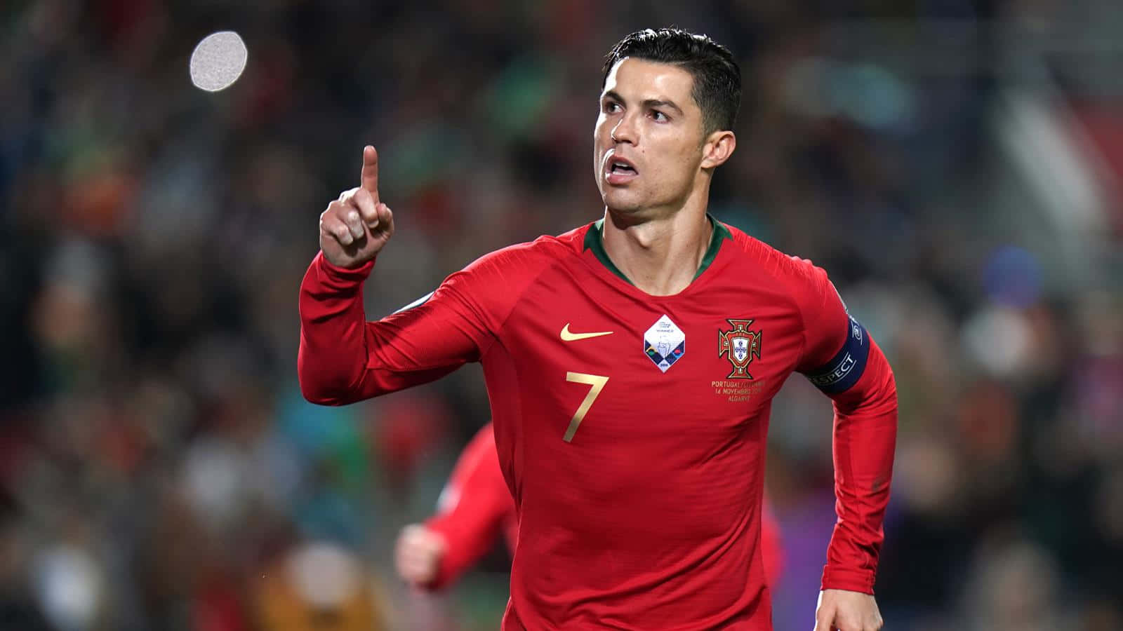 Football Profile 桌布 壁紙 — 克里斯蒂亞諾·羅納度身穿紅色葡萄牙7號球衣，在夜間球場比賽中向上指，充滿力量。