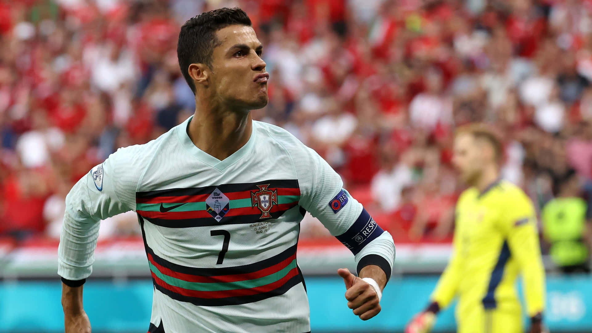 Ronaldo 桌布 壁紙 — 克里斯蒂亞諾·羅納度身穿葡萄牙白色球衣，帶有紅綠條紋，在座無虛席的球場上豎起大拇指慶祝進球。