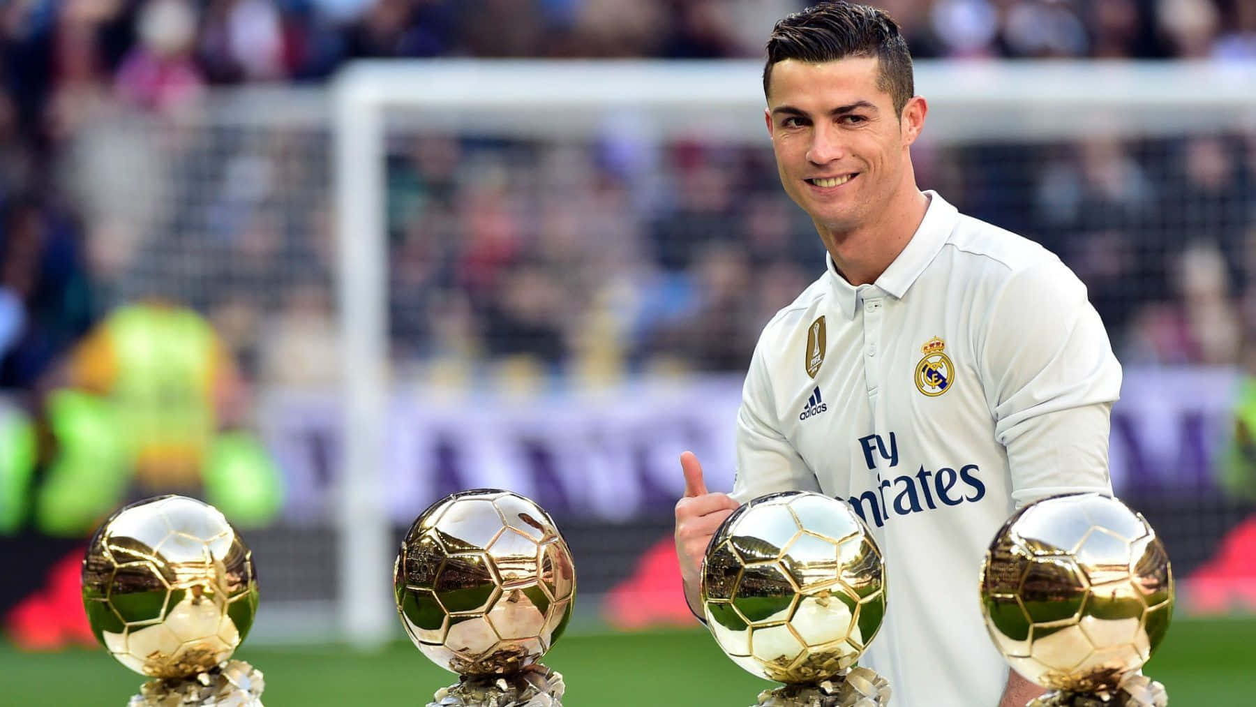 Ronaldo 桌布 壁紙 — 克里斯蒂亞諾羅納度在足球場上自豪地微笑，手持四個金色金球獎獎盃。