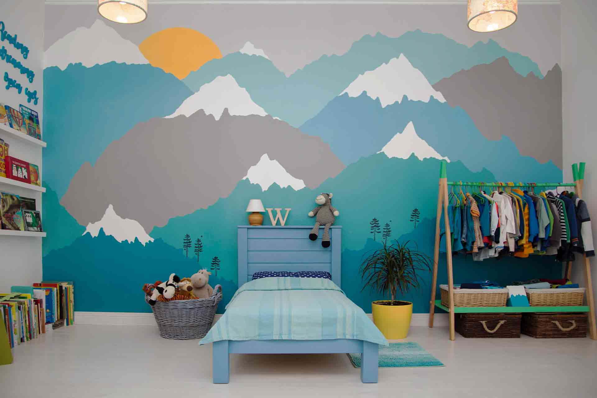 Wall Painting 桌布 壁紙 — 兒童臥室設有充滿活力的山脈壁畫，配有升起的太陽、藍色床和色彩繽紛的衣架。