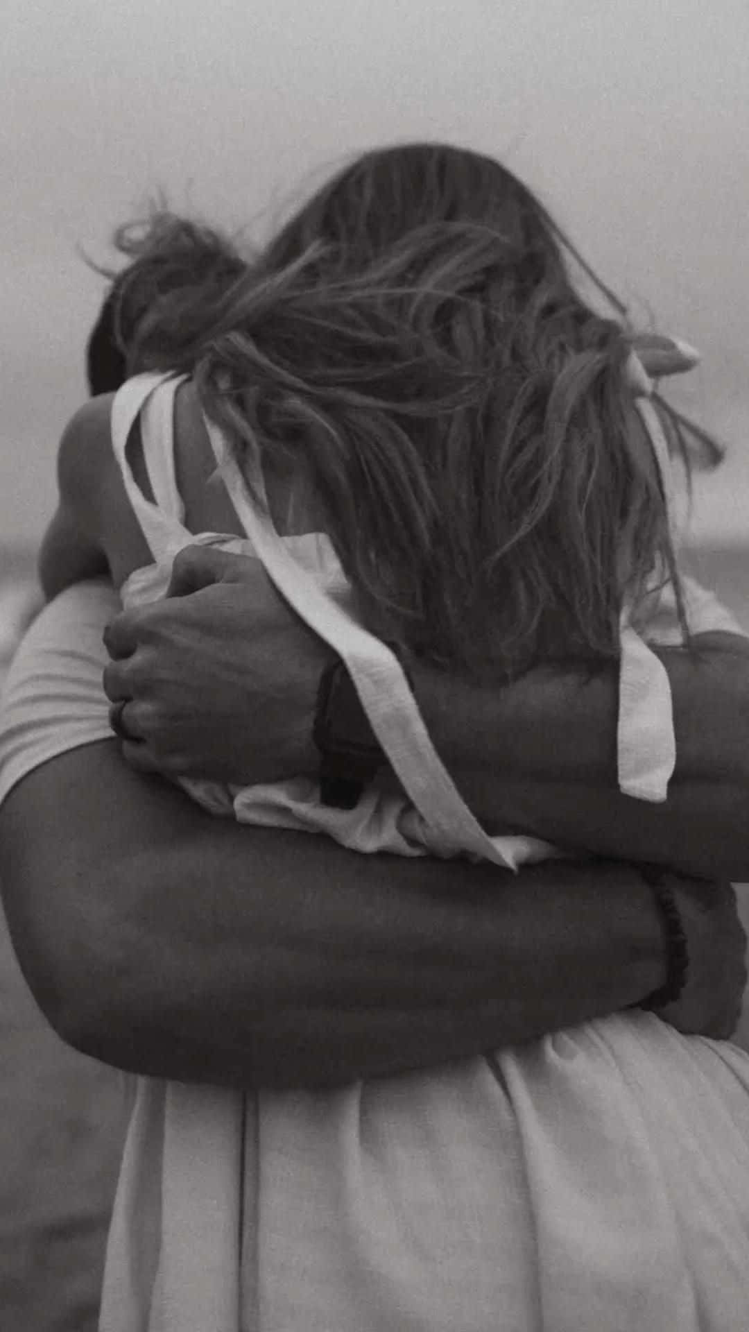 Hugging 桌布 壁紙 — 兩人在溫柔的黑白照片中緊緊擁抱，風吹亂他們的頭髮。