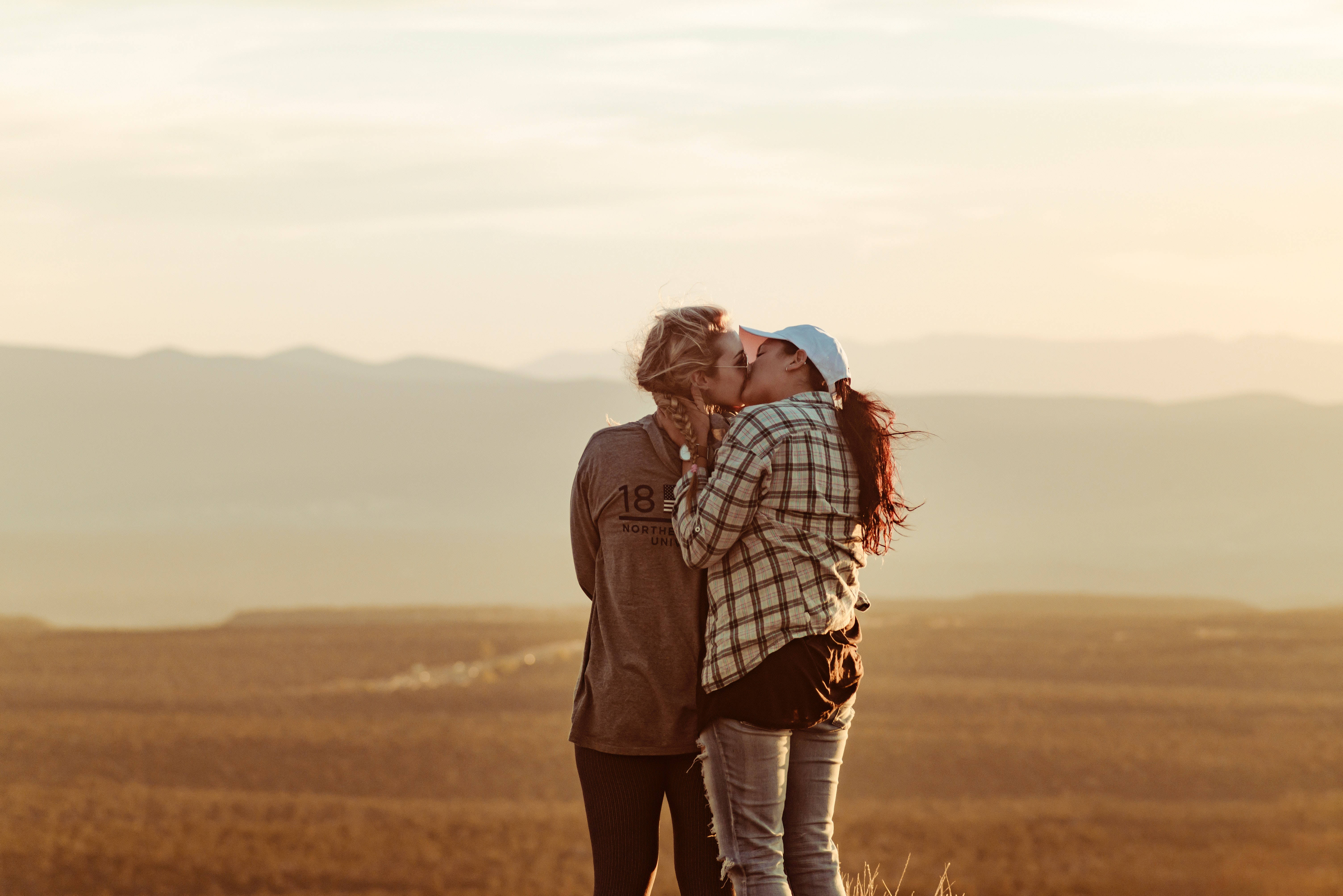 Romantic Love 桌布 壁紙 — 兩人在陽光明媚的山頂上熱情接吻，俯瞰遠山，正值黃金時刻。