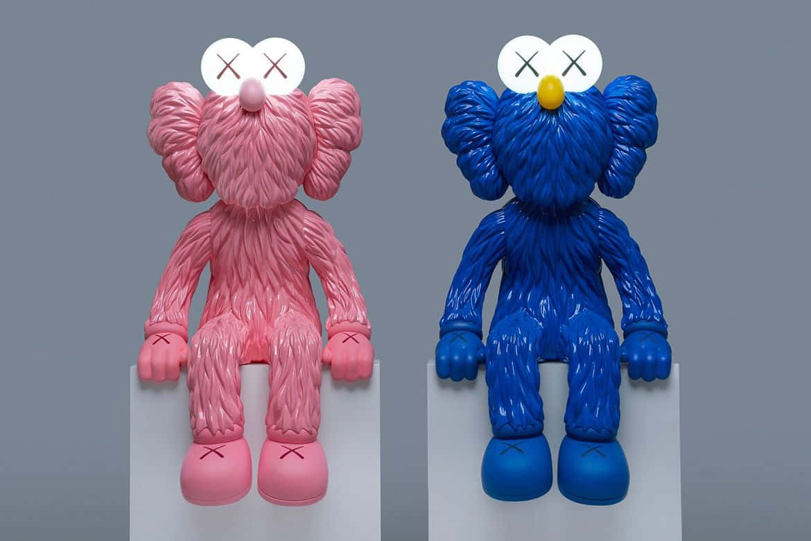KAWS 桌布 壁紙 — 兩件光滑的粉紅色和藍色KAWS Companion雕塑並排坐在白色底座上，背景為中性灰色。