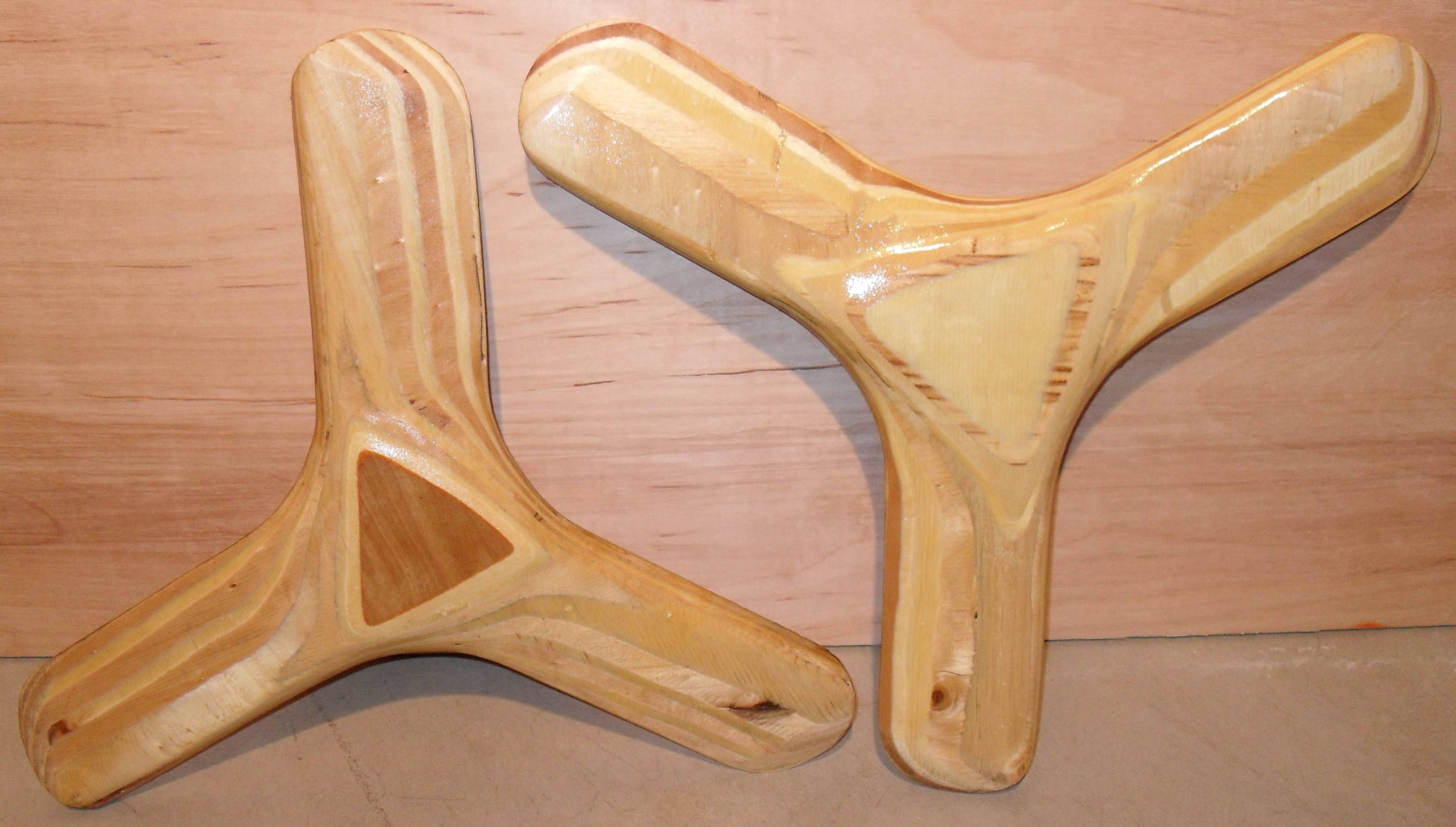 Boomerang 桌布 壁紙 — 兩件手工製作的木製迴力鏢，帶有天然木紋圖案，放置在淺色木質表面上。