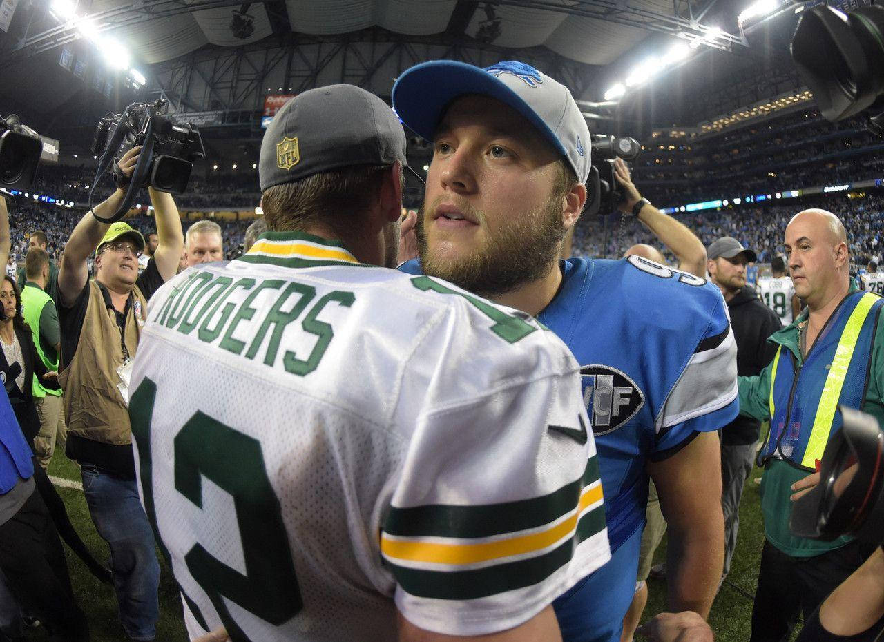 Matthew Stafford 桌布 壁紙 — 兩位NFL四分衛穿著球衣，在明亮的燈光下，於球迷和攝影機環繞的球場上握手。