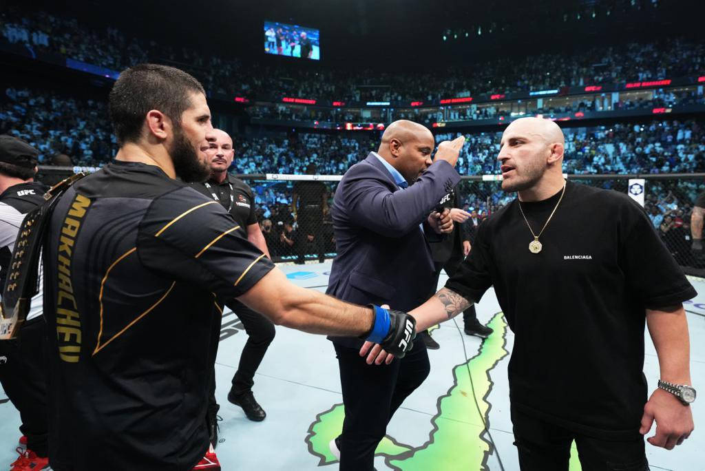 Champion 桌布 壁紙 — 兩位UFC拳手在八角籠中對峙，裁判在緊張的賽前時刻介入。