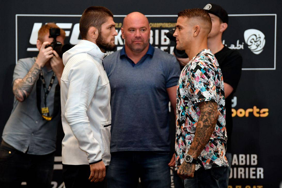 MMA 桌布 壁紙 — 兩位UFC拳手在稱重儀式上對峙，中間站著一位嚴肅的官員，攝影師捕捉了這個緊張的時刻。