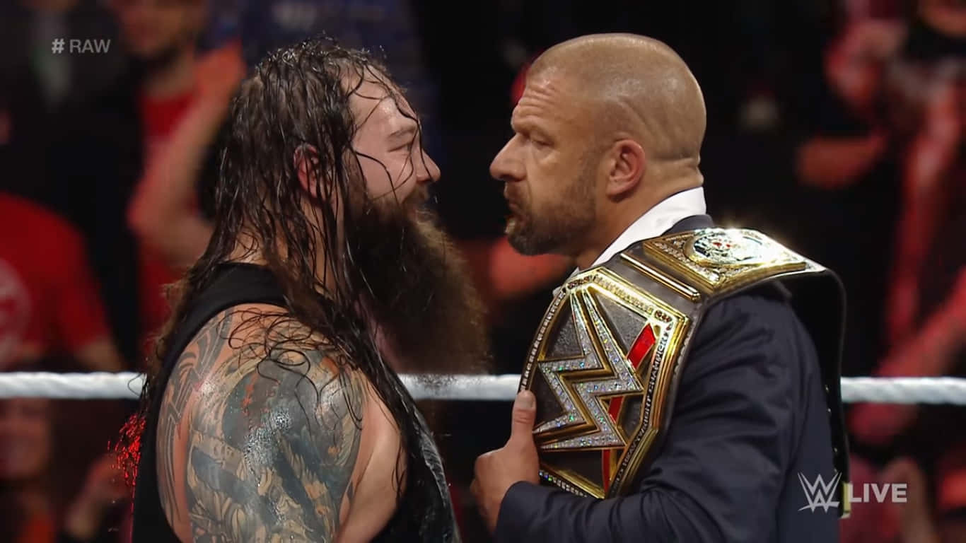 WWE 桌布 壁紙 — 兩位WWE摔角手在擂台上激烈對峙，一人手持冠軍腰帶，另一人有刺青肩膀和濕頭髮。