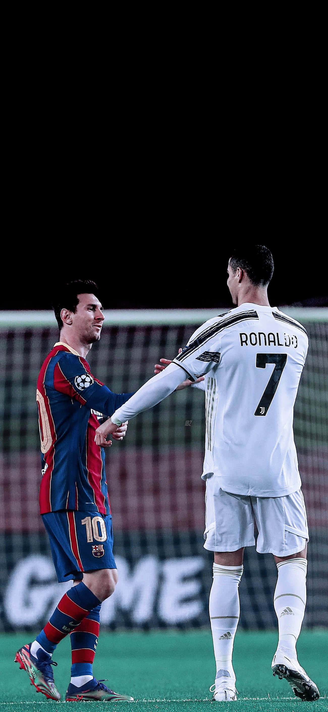 Messi And Ronaldo 4K 桌布 壁紙 — 兩位傳奇足球員梅西和C羅在球場燈光下，於明亮照明的綠色球場上握手。