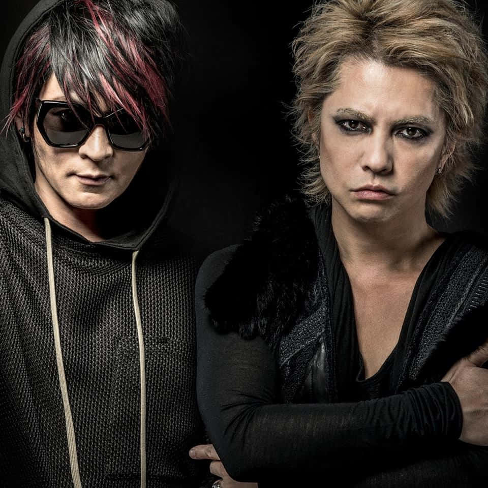 Visual Kei 桌布 壁紙 — 兩位前衛音樂人，擁有誇張髮型和深色妝容，在黑色背景下強烈擺姿勢。
