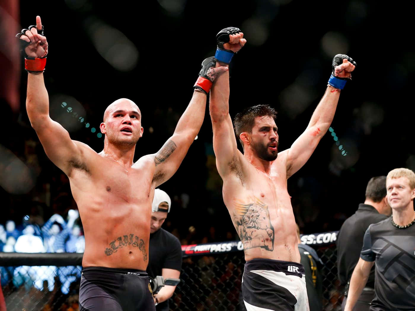iPhone 桌布 壁紙 — 兩位勝利的MMA拳手在燈光明亮的八角籠內高舉雙臂慶祝勝利，背景是模糊的人群。
