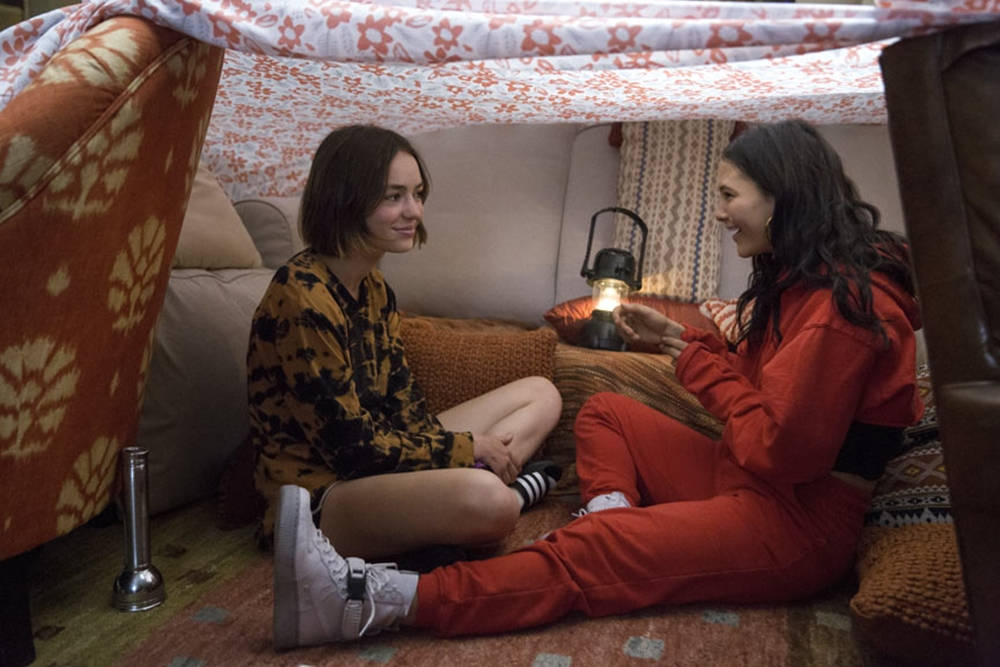Netflix 桌布 壁紙 — 兩位女士在溫暖的燈籠照亮下，於舒適地毯上的圖案毛氈堡壘中一起大笑。