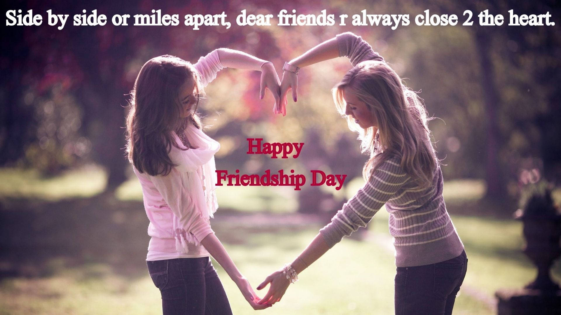 Friendship Day 桌布 壁紙 — 兩位女士在陽光明媚的公園裡手牽手，用手比出心形，慶祝友誼日。