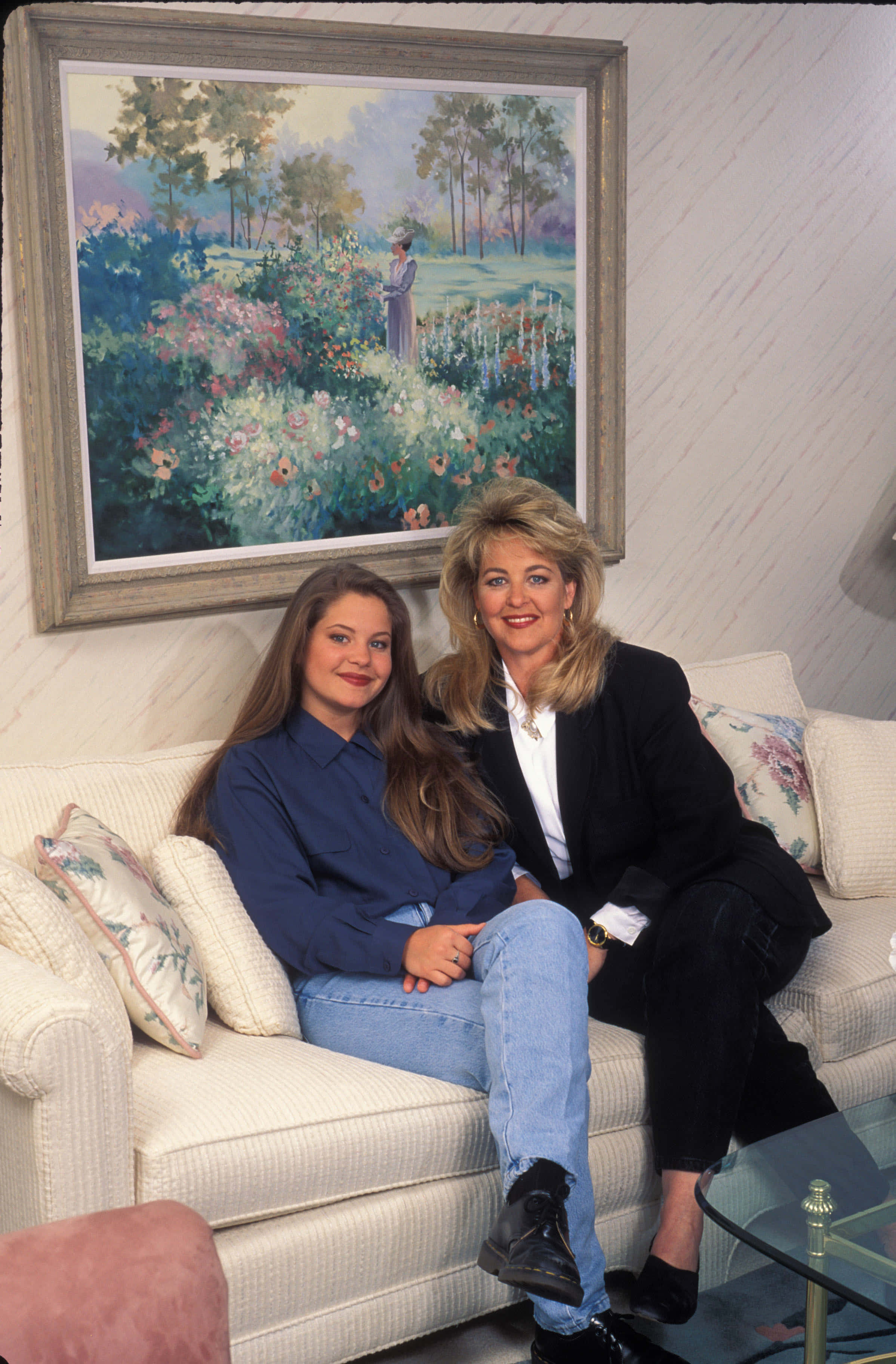 candace cameron bure 桌布 壁紙 — 兩位女士坐在奶油色沙發上，在大型裱框花園花卉畫作下微笑。