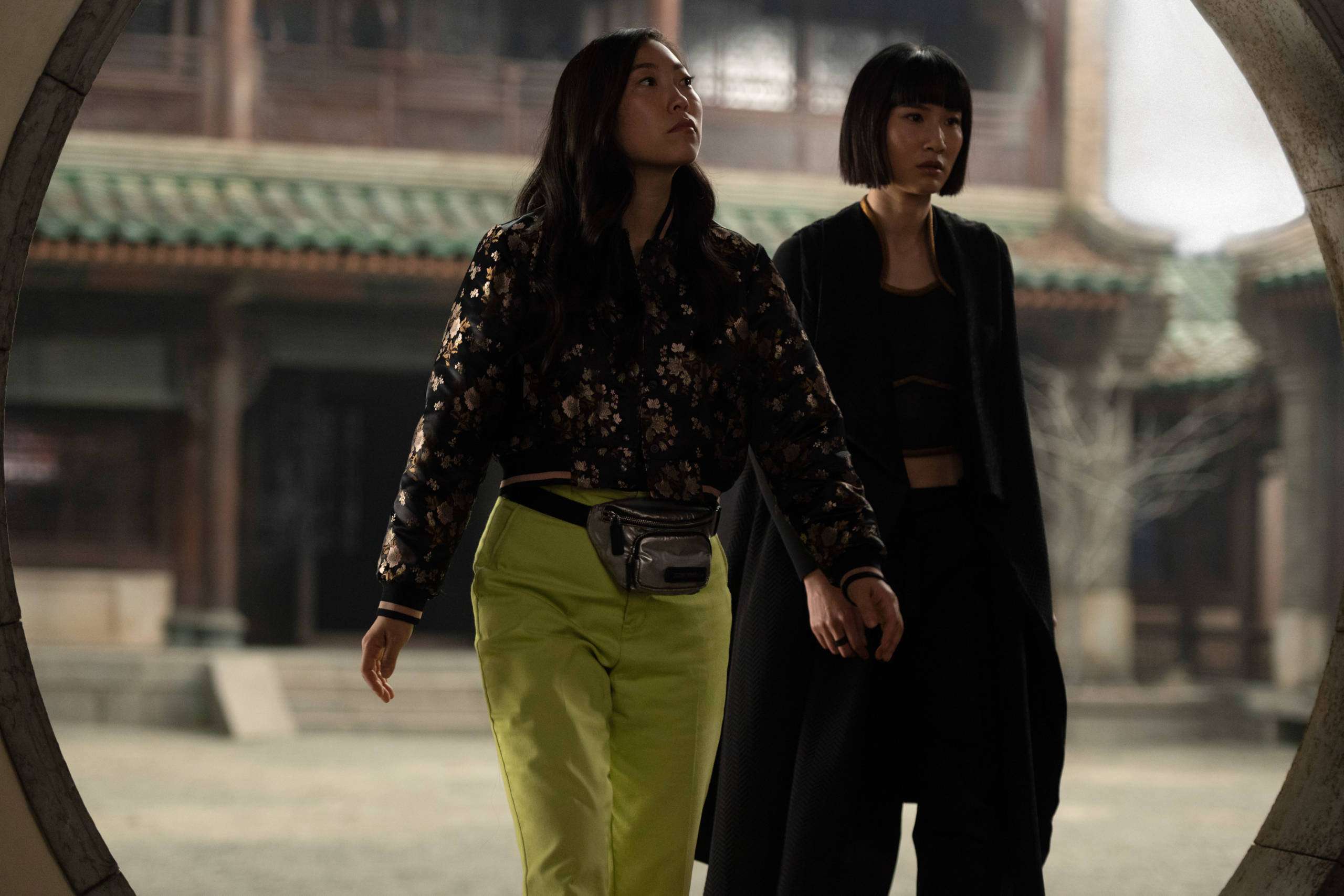 Shang 桌布 壁紙 — 兩位女士穿過一個圓形石拱門，進入一個擁有華麗瓦片屋頂的傳統庭院。