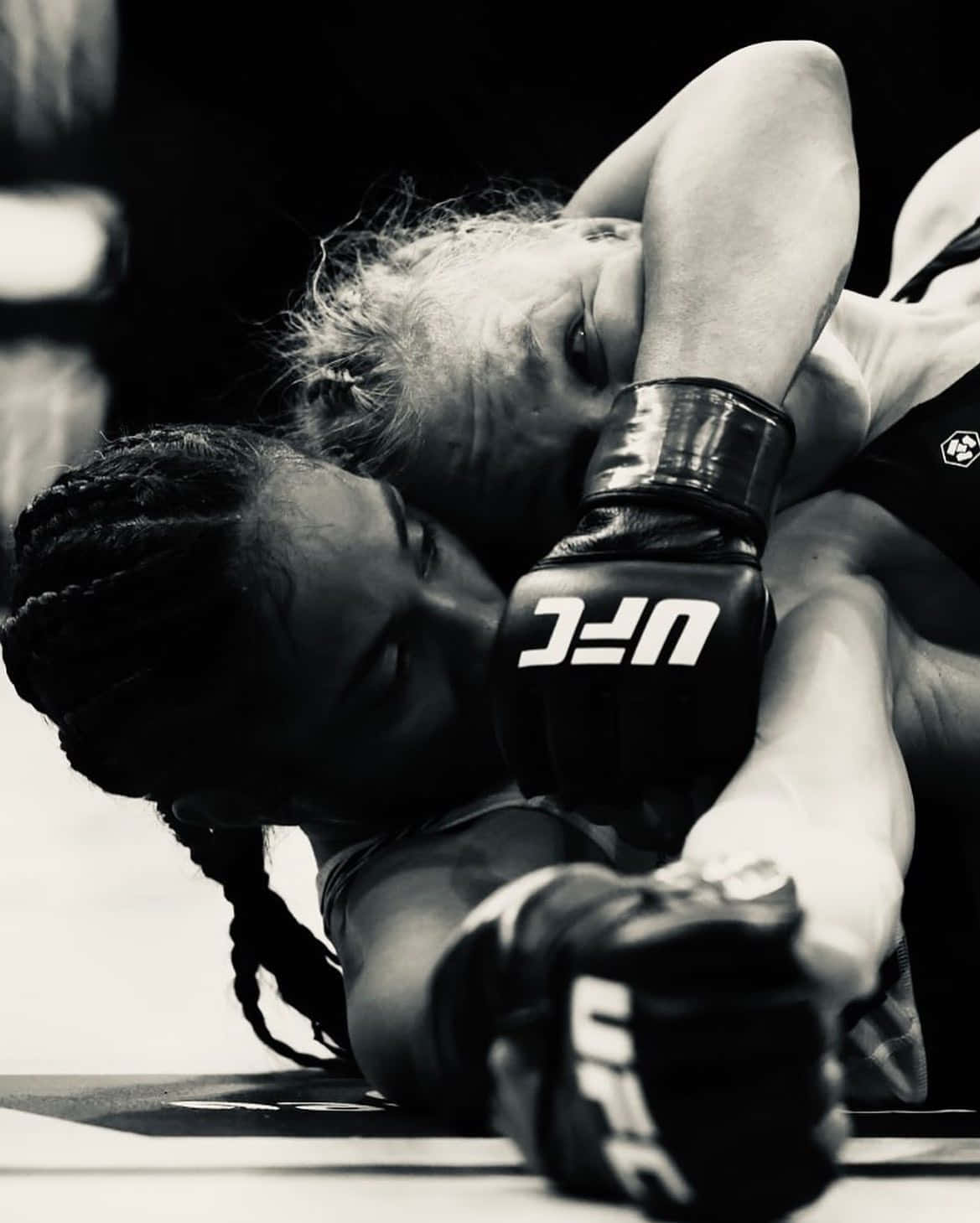 UFC 桌布 壁紙 — 兩位女性MMA拳手在黑暗的墊子上，在戲劇性的黑白燈光下進行緊張的纏鬥。