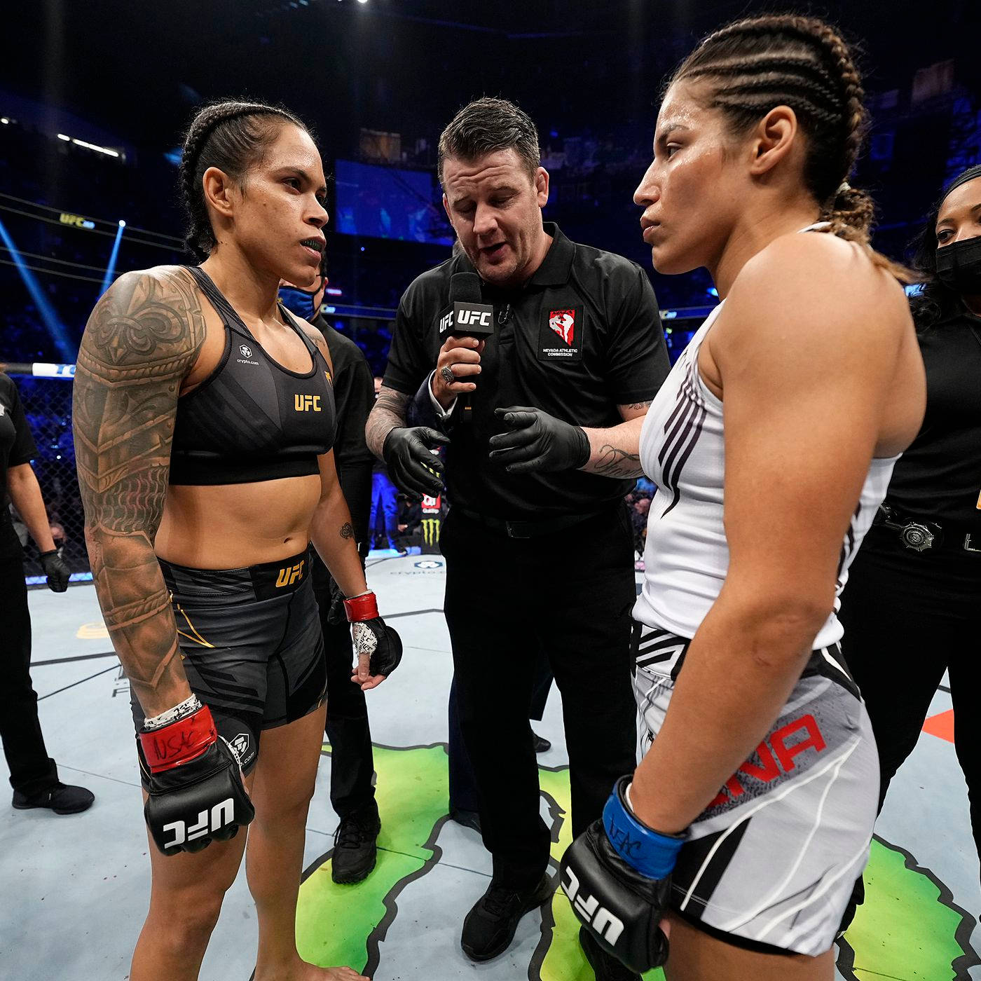 UFC 桌布 壁紙 — 兩位女性UFC拳手在八角籠中對峙，裁判在她們之間拿著麥克風。