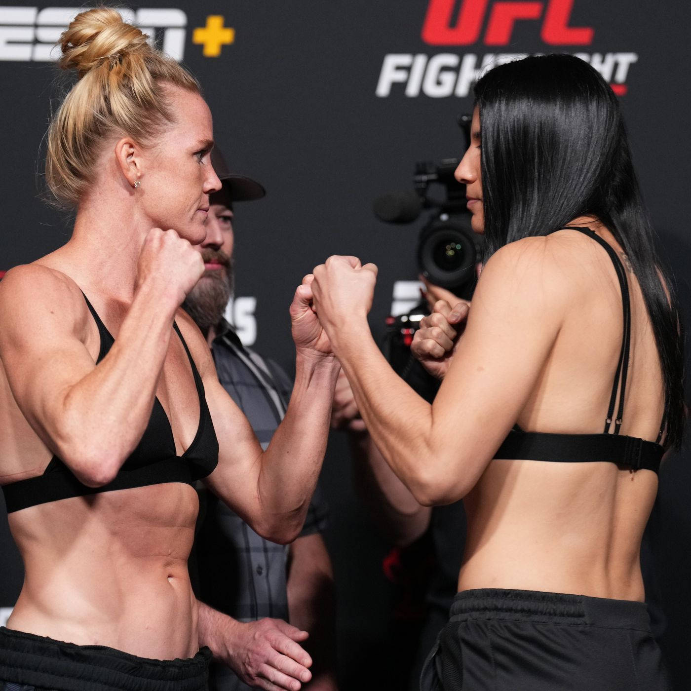 UFC 桌布 壁紙 — 兩位女性UFC拳手在明亮的攝影棚燈光下，於緊張的賽前對峙中鎖住拳頭。