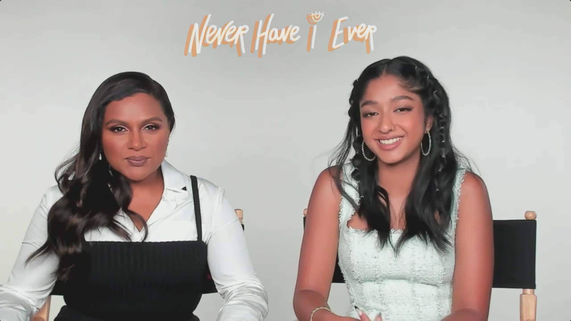tv 桌布 壁紙 — 兩位女性微笑著坐在導演椅上，背景是素色牆壁，上方有「Never Have I Ever」字樣。