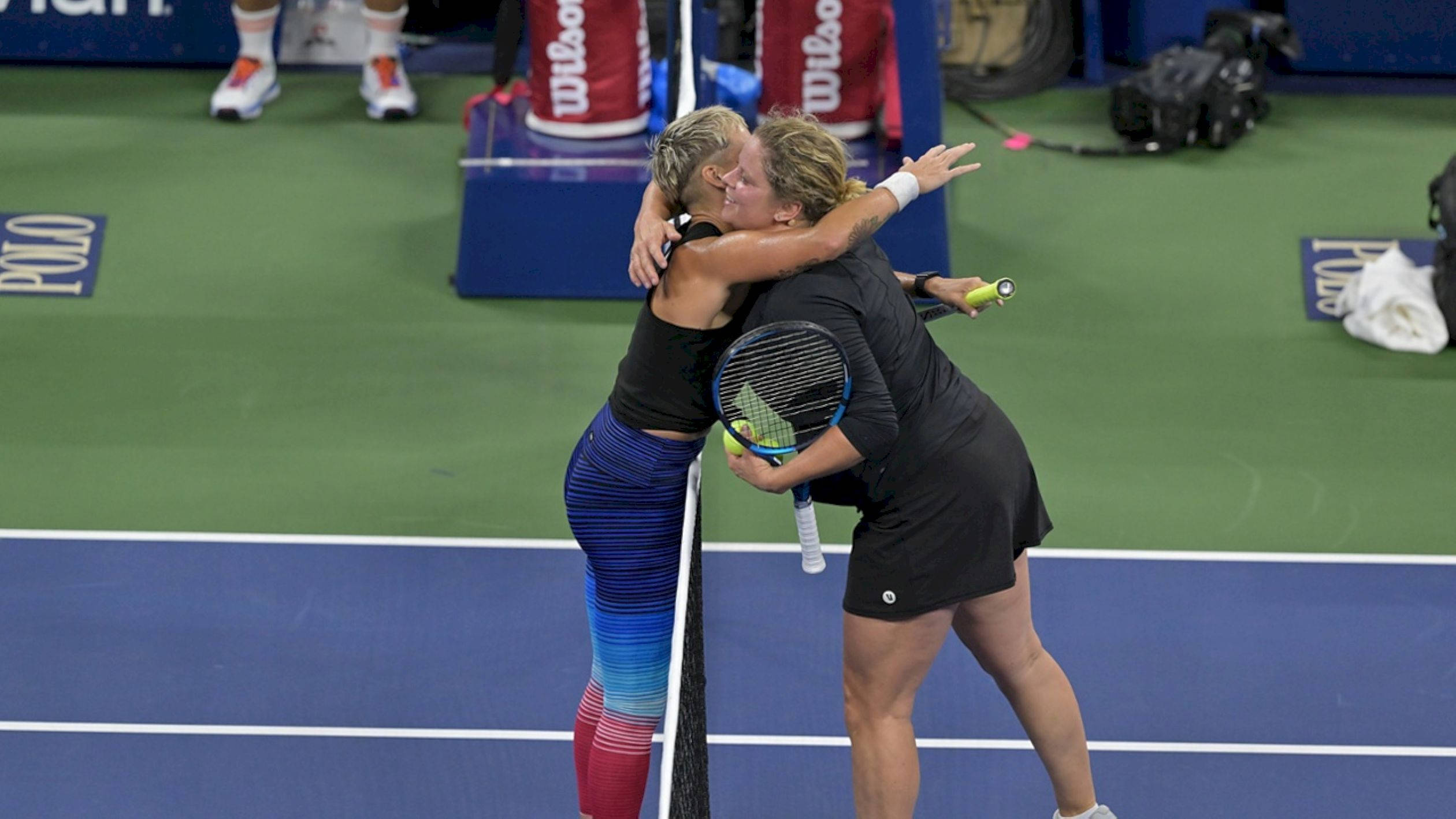 Hug 桌布 壁紙 — 兩位女網球選手在充滿活力的藍綠色球場上隔網熱情擁抱。