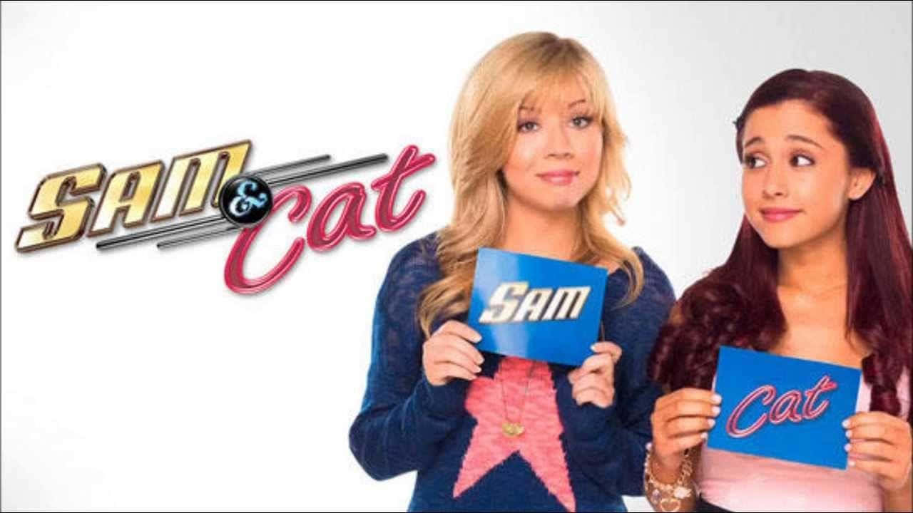Sam And Cat 桌布 壁紙 — 兩位年輕女性在白色背景前手持藍色標語牌，上面寫著 Sam 和 Cat，並帶有節目標誌。