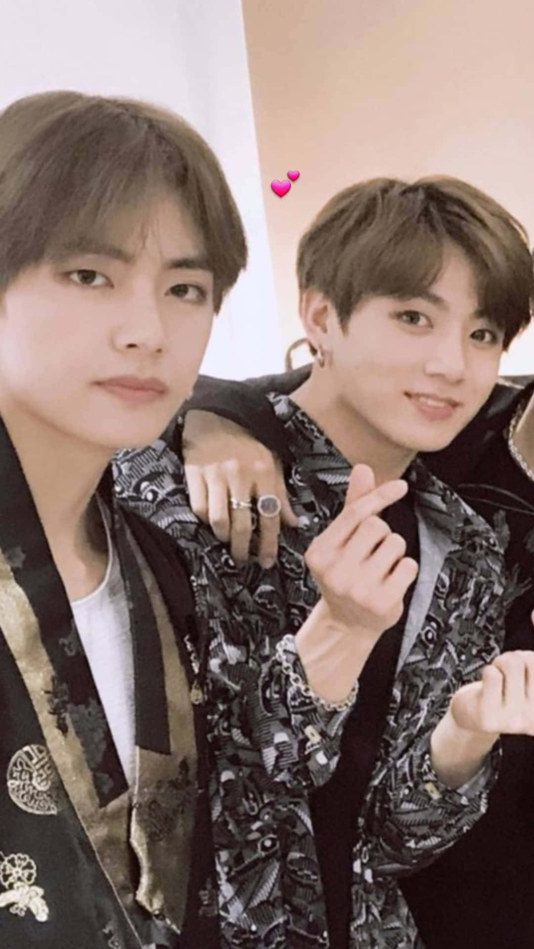 BTS 桌布 壁紙 — 兩位年輕男士身穿時尚圖案外套，緊密擺姿勢，其中一人做出手指愛心手勢。