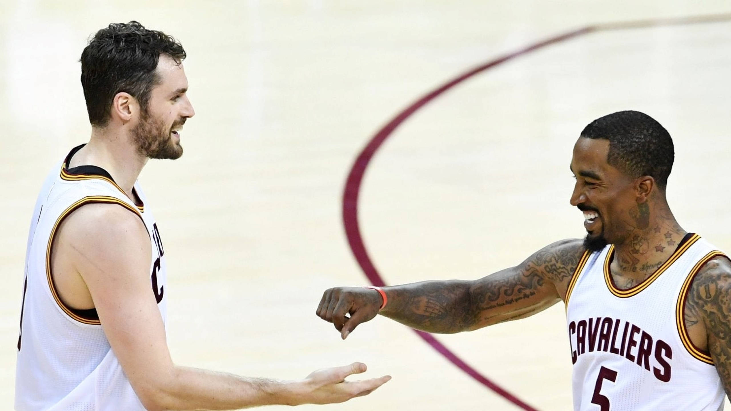 Kevin Love 桌布 壁紙 — 兩位微笑的克里夫蘭騎士隊籃球運動員在球場上互相碰拳，背景有紅色弧線。