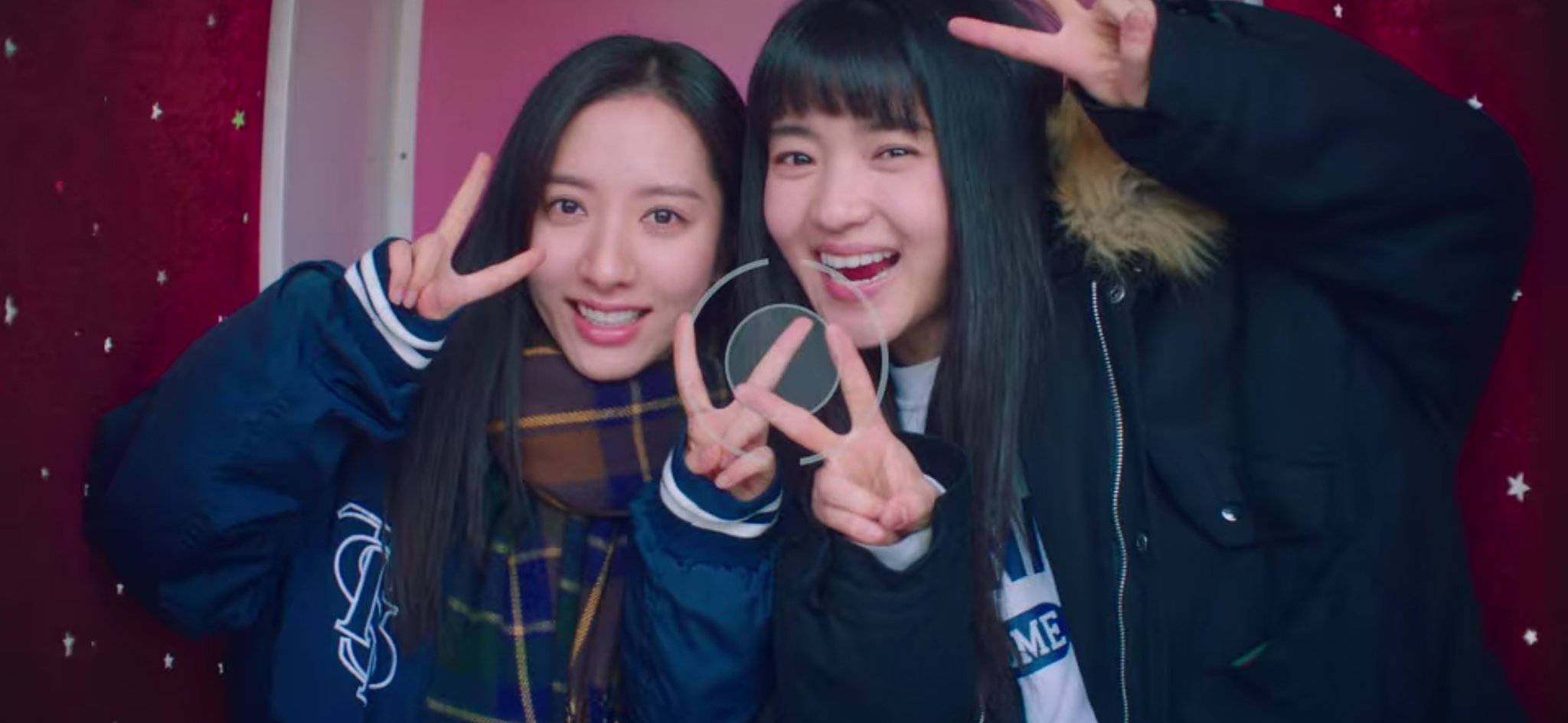 Teenage Girls 桌布 壁紙 — 兩位微笑的年輕女性在滿天星的紅色背景前開心地擺姿勢，用手做出和平手勢。