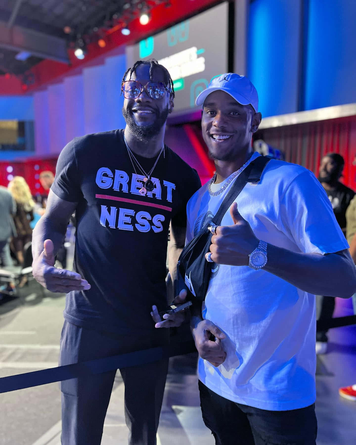 MMA 桌布 壁紙 — 兩位微笑的男子在一個充滿活力的活動中一起擺姿勢，背景有色彩繽紛的舞台燈光和人群。