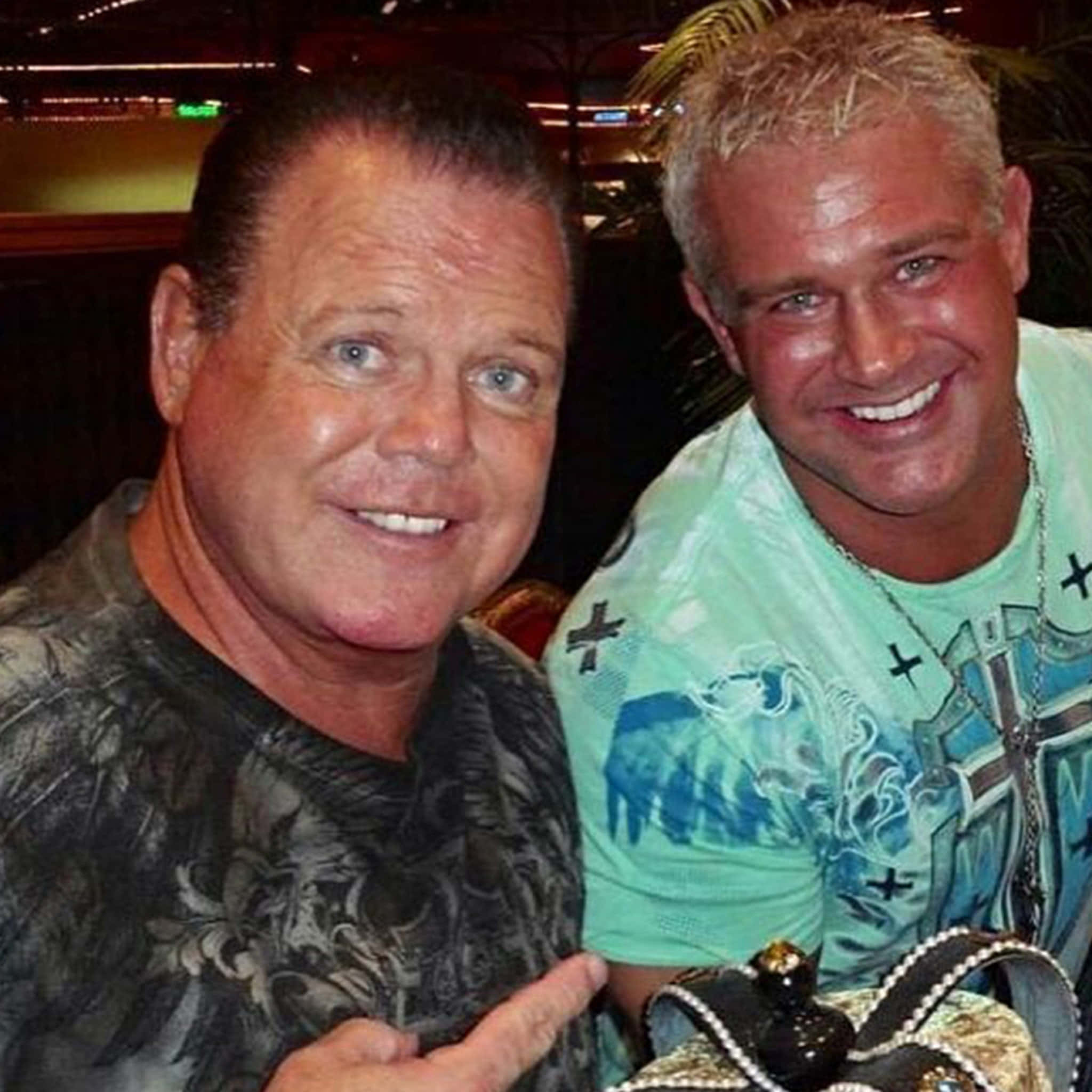 Brian Christopher 桌布 壁紙 — 兩位微笑的男子在室內一起擺姿勢，其中一人手持冠軍腰帶，背景有模糊的燈光。
