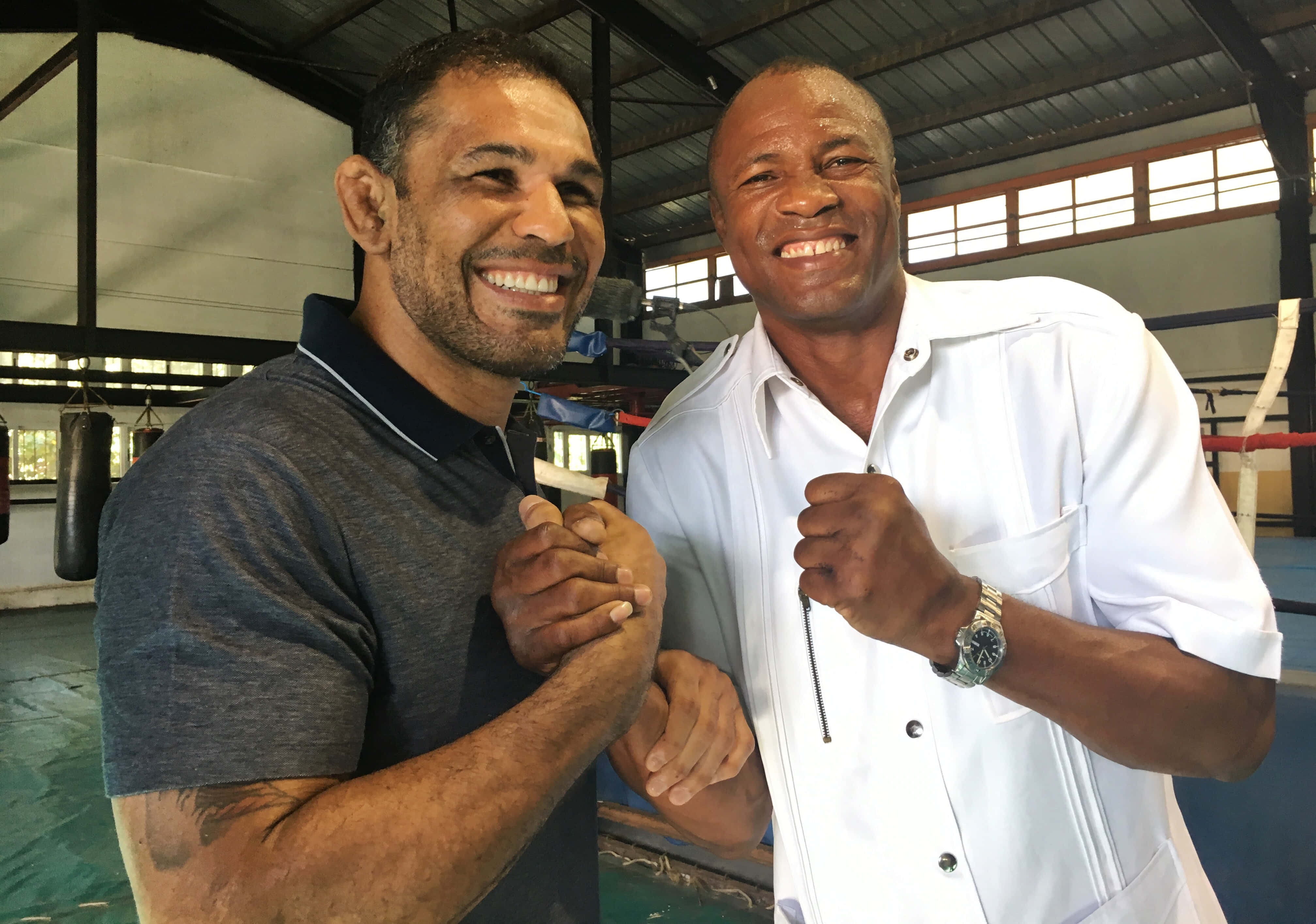 MMA 桌布 壁紙 — 兩位微笑的男子在拳擊館中交臂，其中一人舉起拳頭以示友誼。