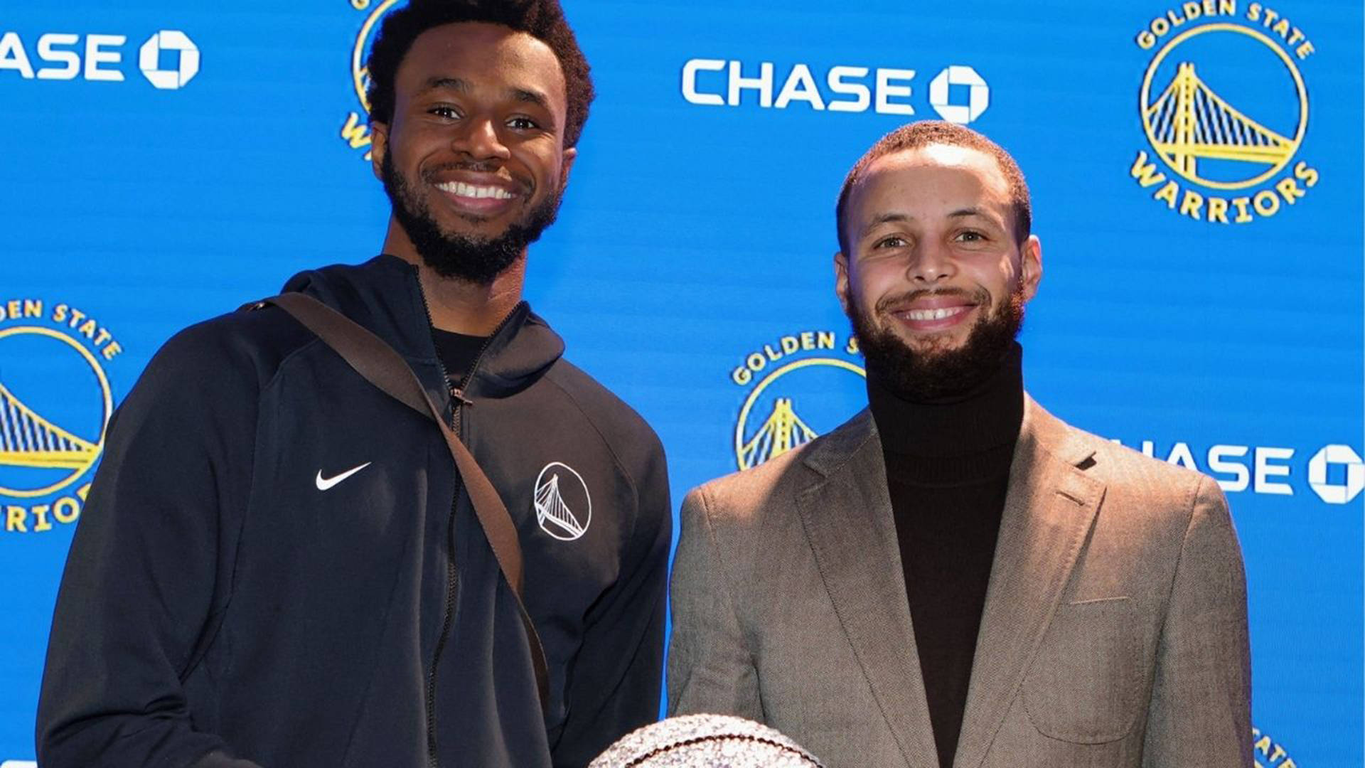 Andrew Wiggins 桌布 壁紙 — 兩位微笑的籃球運動員一起拿著籃球，在藍色金州勇士隊背景前擺姿勢。
