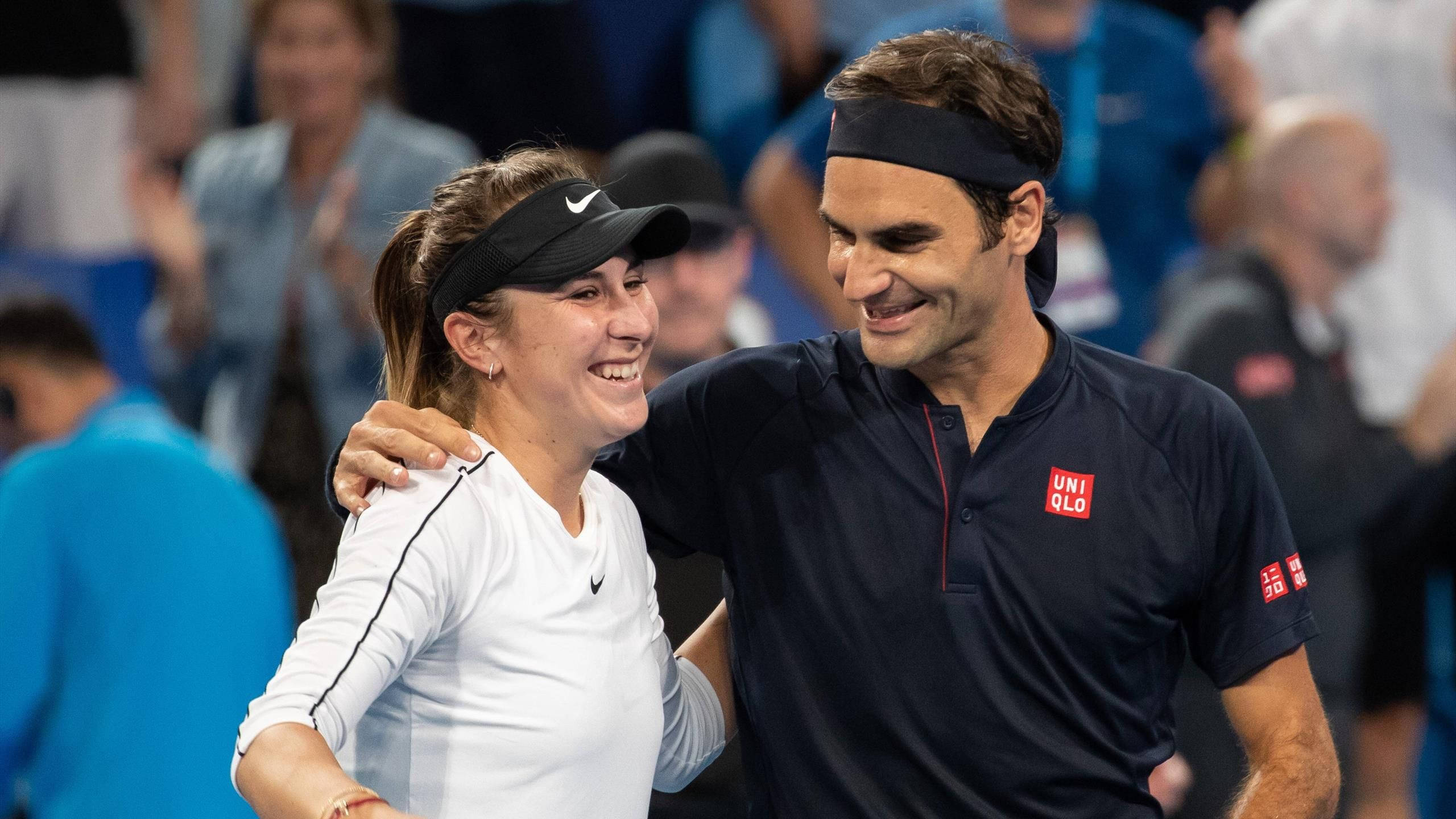 Athlete 桌布 壁紙 — 兩位微笑的網球選手在球場上熱情擁抱，背景是模糊的觀眾。