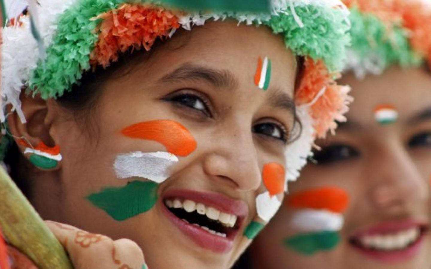 Indian 桌布 壁紙 — 兩位快樂的女孩臉上畫著印度國旗，戴著節日氣氛的綠色、橙色、白色頭帶，笑容燦爛。