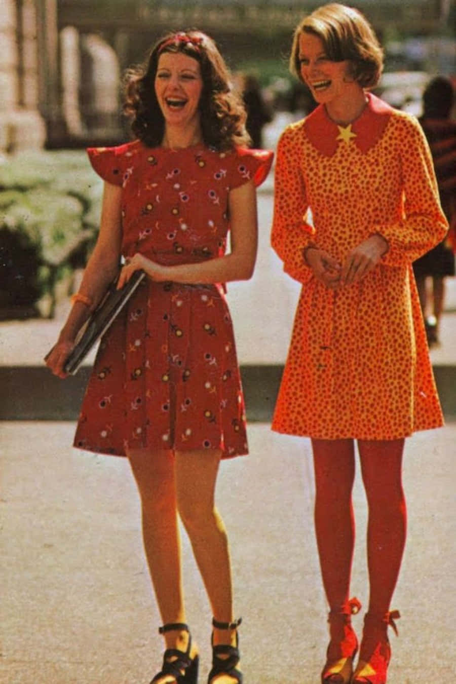 70年代動圖 桌布 壁紙 — 兩位快樂的女性穿著充滿活力的1960年代花卉和圓點連衣裙，在陽光明媚的日子裡笑著走在戶外。