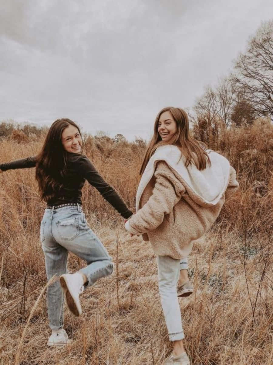 Friends 桌布 壁紙 — 兩位快樂的朋友在陰天的高大金色草叢中笑著旋轉。