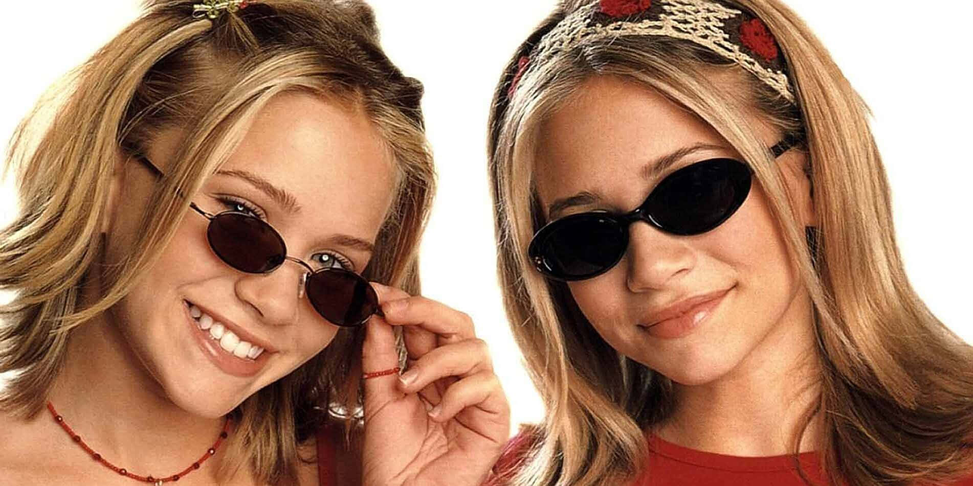 twins 桌布 壁紙 — 兩位戴著太陽眼鏡、微笑的金髮女孩在明亮的白色背景前緊密地擺姿勢。