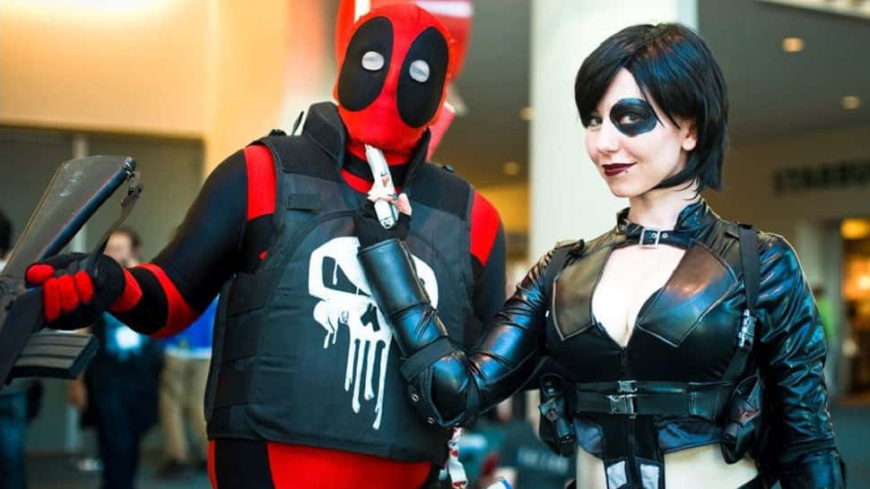 Deadpool And Domino 桌布 壁紙 — 兩位扮演死侍和黑寡婦的角色扮演者，身穿精緻服裝和道具，在展會上自信地擺姿勢。